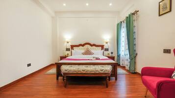 A bedroom with a wooden bed, a red chair, and a nightstand with lamps.