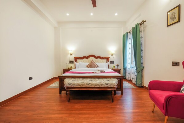A bedroom with a wooden bed, a red chair, and a nightstand with lamps.