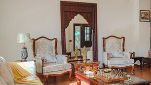 A traditional living room with two ornate armchairs, a sofa, a coffee table with a chess set, and a colorful box. - amã Stays & Trails White Hackle, Dharamshala (Dharamshala)