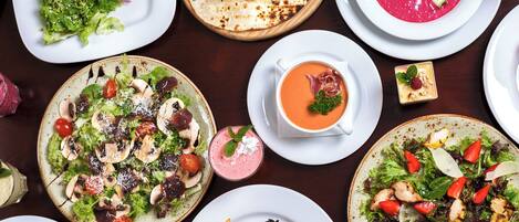 Variedad de platos que incluyen ensaladas, pescado a la parrilla y un tazón de sopa, lo que sugiere una amplia selección de comidas.