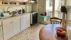 Een keuken met witte kasten, een fornuis en een eettafel met een mand vol fruit.
