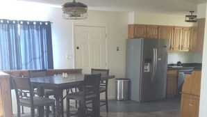 A spacious living room with a large sofa, a dining area with a table and chairs, and a kitchen with wooden cabinets and appliances. - Welcoming 2-bedroom house in Bailey perfect for your getaway. (Bailey)