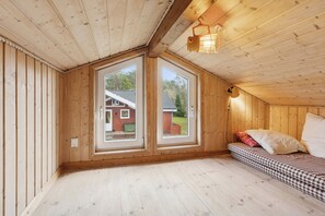 Une pièce en bois avec un lit, de grandes fenêtres et un luminaire au plafond.