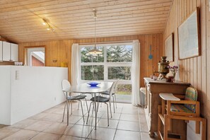 Un intérieur en bois comprenant une table à manger, des chaises, une fenêtre et une petite cuisine.