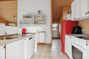 A kitchen with white cabinets, a red refrigerator, and a stove. - Peaceful cottage near beach and nature (Hadsund)