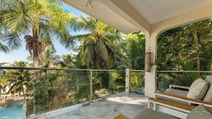 Un balcon avec une piscine, entouré de palmiers et offrant une vue dégagée sur le ciel.