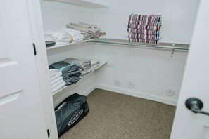 A closet with shelves holding folded clothes and a hanging rack with striped towels. - Cozy Cabin Getaway Above Park City With Hot Tub (Summit County)