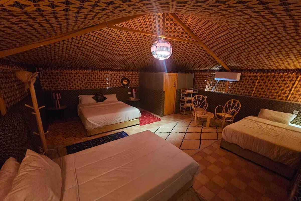 Una habitación acogedora tipo tienda de campaña, con dos camas, una mesita y una silla.
