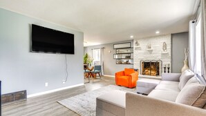 A modern living room with a flat-screen TV, a fireplace, and a sofa.