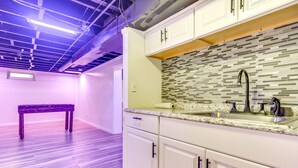 A modern kitchen with white cabinets, a tiled backsplash, and a granite countertop.