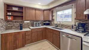 A modern kitchen with wooden cabinets, a stainless steel dishwasher, a coffee maker, and a microwave.
