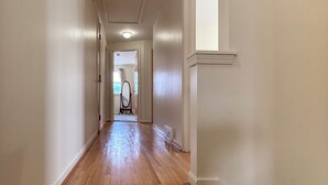 A long, narrow hallway with wooden floors and white walls.