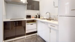 Una cucina moderna con mobili bianchi, forno integrato e cappa aspirante in acciaio inossidabile.