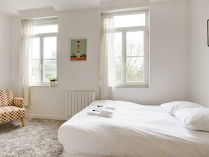 A bedroom with a bed, a chair, a radiator, and a window with a view of trees. - Lilly-Tout à pied, proche gares, Grd Palais&Centre (Lille)