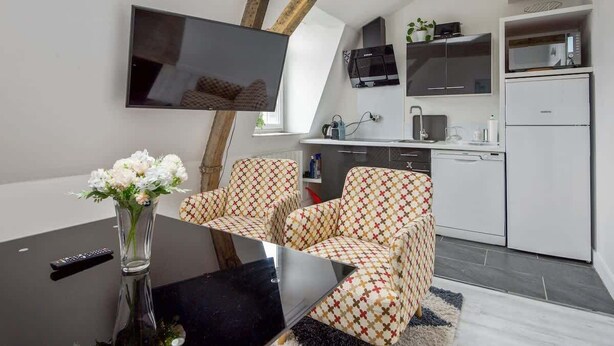Een moderne woonruimte met een eethoek, keuken en een aan de muur bevestigde televisie.