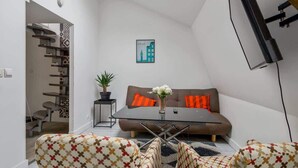 Een modern loftappartement met dakraam, een zithoek, een eettafel en een trap.