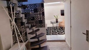 Een modern interieur met een spiltrap, behang en een klein tafeltje met een plant.
