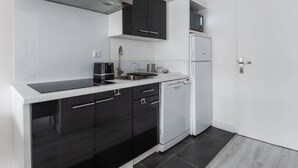 Een moderne keuken met zwarte kastjes, een wit aanrecht en een roestvrijstalen afzuigkap.