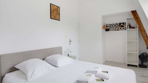 Une chambre d’hôtel moderne avec un grand lit, une table de chevet, une chaise, une armoire et un escalier.