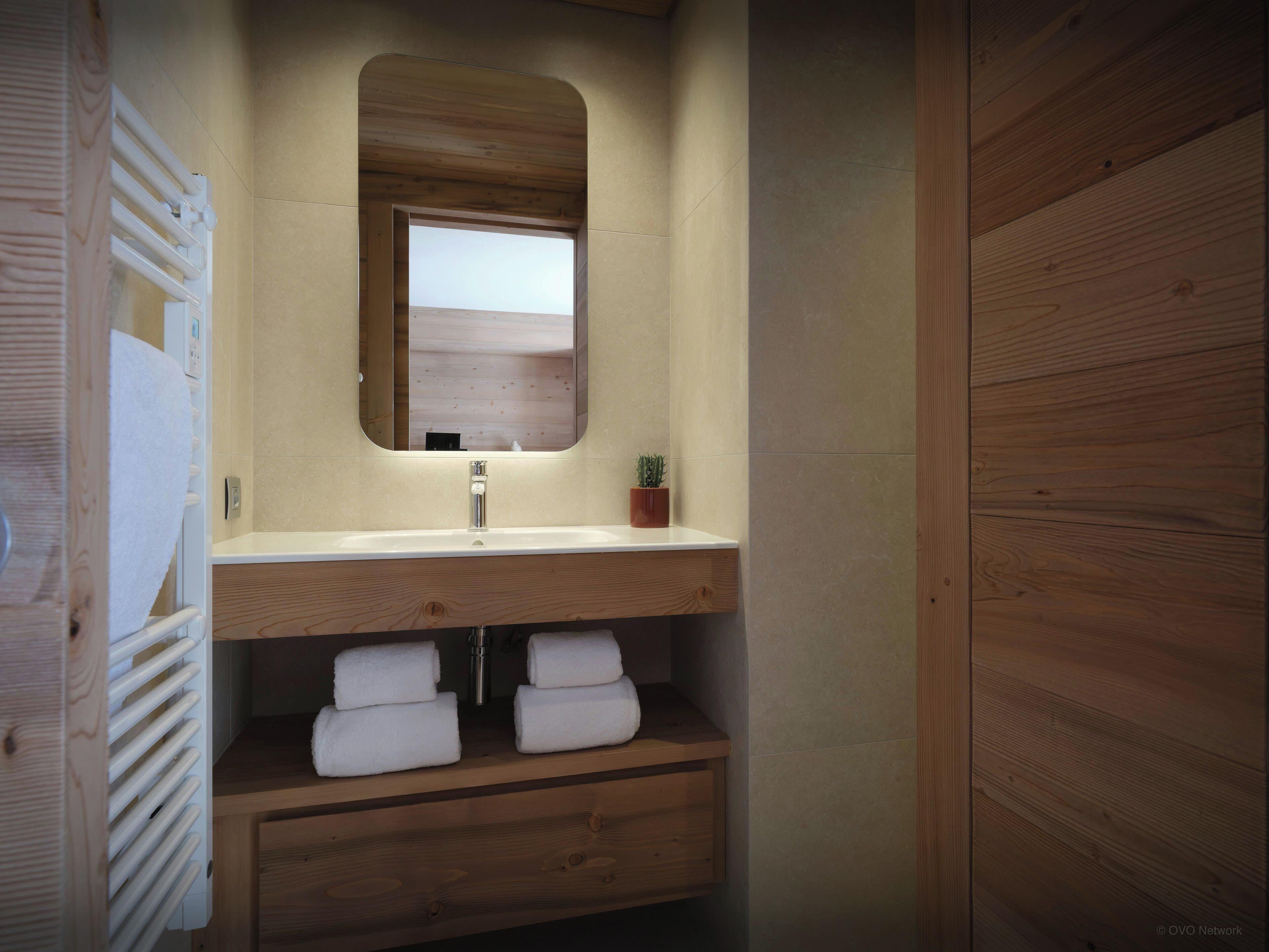 A bathroom with a wooden vanity, a mirror, a sink, and a small potted plant.