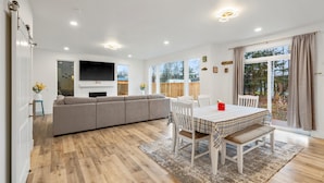 A spacious living room with a large sofa, a dining table with chairs, and a fireplace. - ANCHORAGE HOUSE WITH PEACEFUL PLACE (Anchorage)