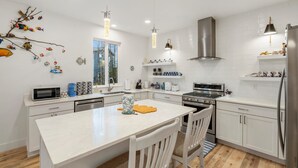A modern kitchen with white cabinetry, stainless steel appliances, and a central island. - ANCHORAGE HOUSE WITH PEACEFUL PLACE (Anchorage)
