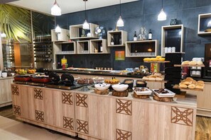 Ein Buffet mit verschiedenen Speisen und Getränken, Holzkabinetten mit verzierten Ausschnitten und hängenden Pendelleuchten.