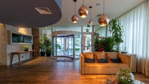 A lobby with a wooden floor, a sofa, a bench, and a glass door leading outside. - Ibis Styles Curitiba Airport Hotel (Sao Jose dos Pinhais)