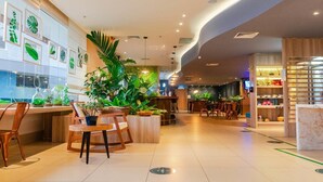 A modern hotel lobby with a reception desk, seating area, and a variety of plants. - Ibis Styles Curitiba Airport Hotel (Sao Jose dos Pinhais)