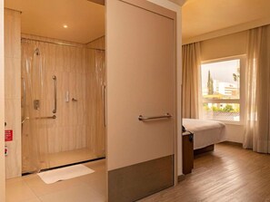 Ein Hotelzimmer mit Dusche, einem Bett und einem Vorhangfenster.