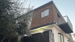 A modern two-story house with a brick facade, a balcony, and a visible garage door.