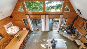 Een houten chalet met hoge plafonds, een eethoek, een bank en een open haard.