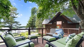 Een houten terras met groene fauteuils en uitzicht op een chalet.