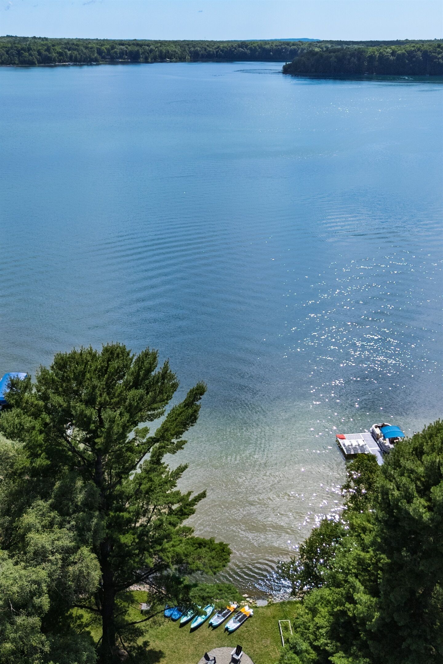 A lakeside view with clear water, boats, and a dock.