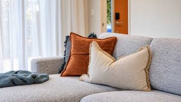 A grey sofa with three pillows in different textures and colors.
