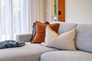 A grey sofa with three pillows in different textures and colors. - Central Richmond | Modern 3BR + Courtyard (Christchurch)