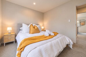 Ein Hotelzimmer mit einem Bett, einem Nachttisch, einer Lampe und einer Tür zu einem anderen Raum.