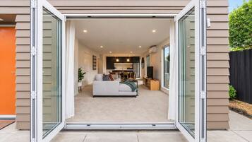 A modern home interior with a living room, kitchen, and dining area visible through a sliding glass door.