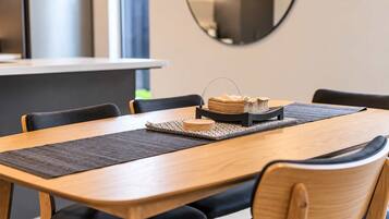 A dining area with a wooden table, black chairs, a placemat, and a tray with napkins and a small bowl.