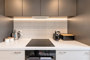 A modern kitchen with a built-in induction cooktop, a coffee machine, and a kettle. - Central Richmond | Modern 3BR + Courtyard (Christchurch)