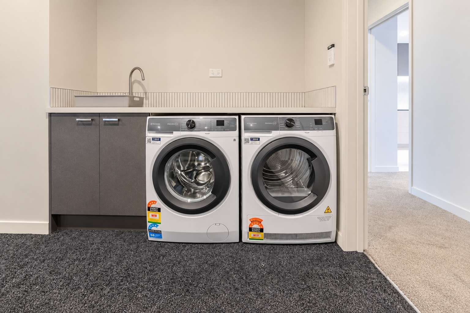 A laundry room with two front-loading washing machines and a grey cabinet.