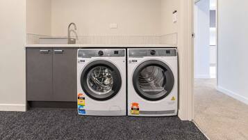A laundry room with two front-loading washing machines and a grey cabinet.