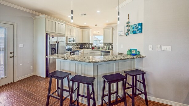 A kitchen with a central island, bar stools, and pendant lighting. - Blissful Waves - Pet Friendly, Walk to the Beach! (Bolivar Peninsula)