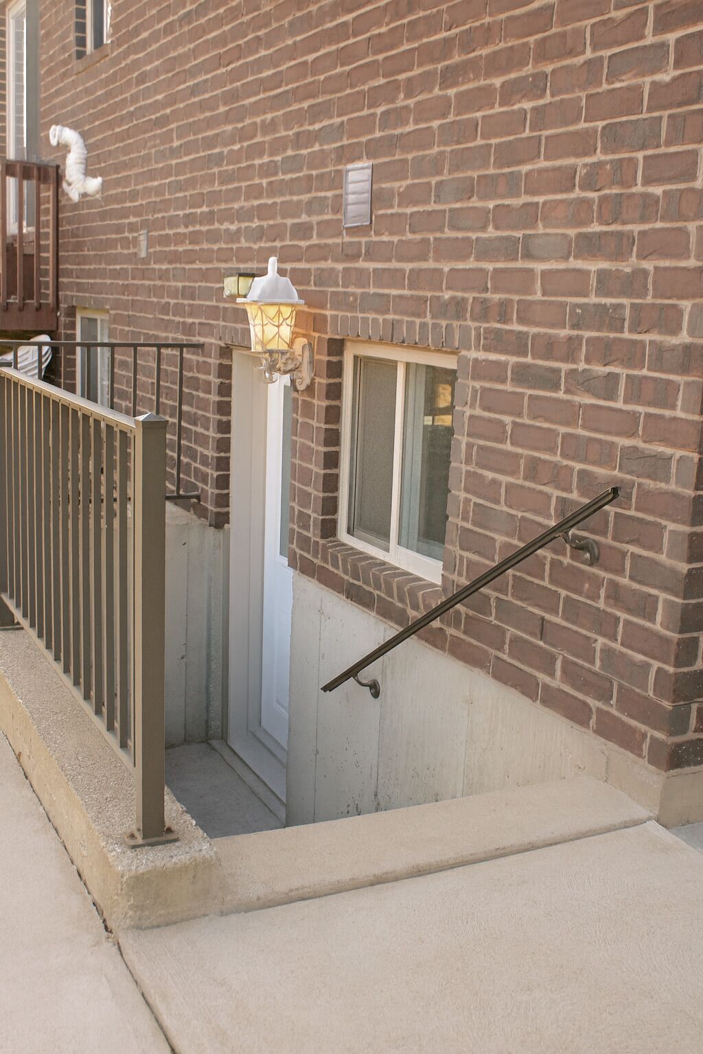 A brick building with a metal gate, a small window, and a light fixture.