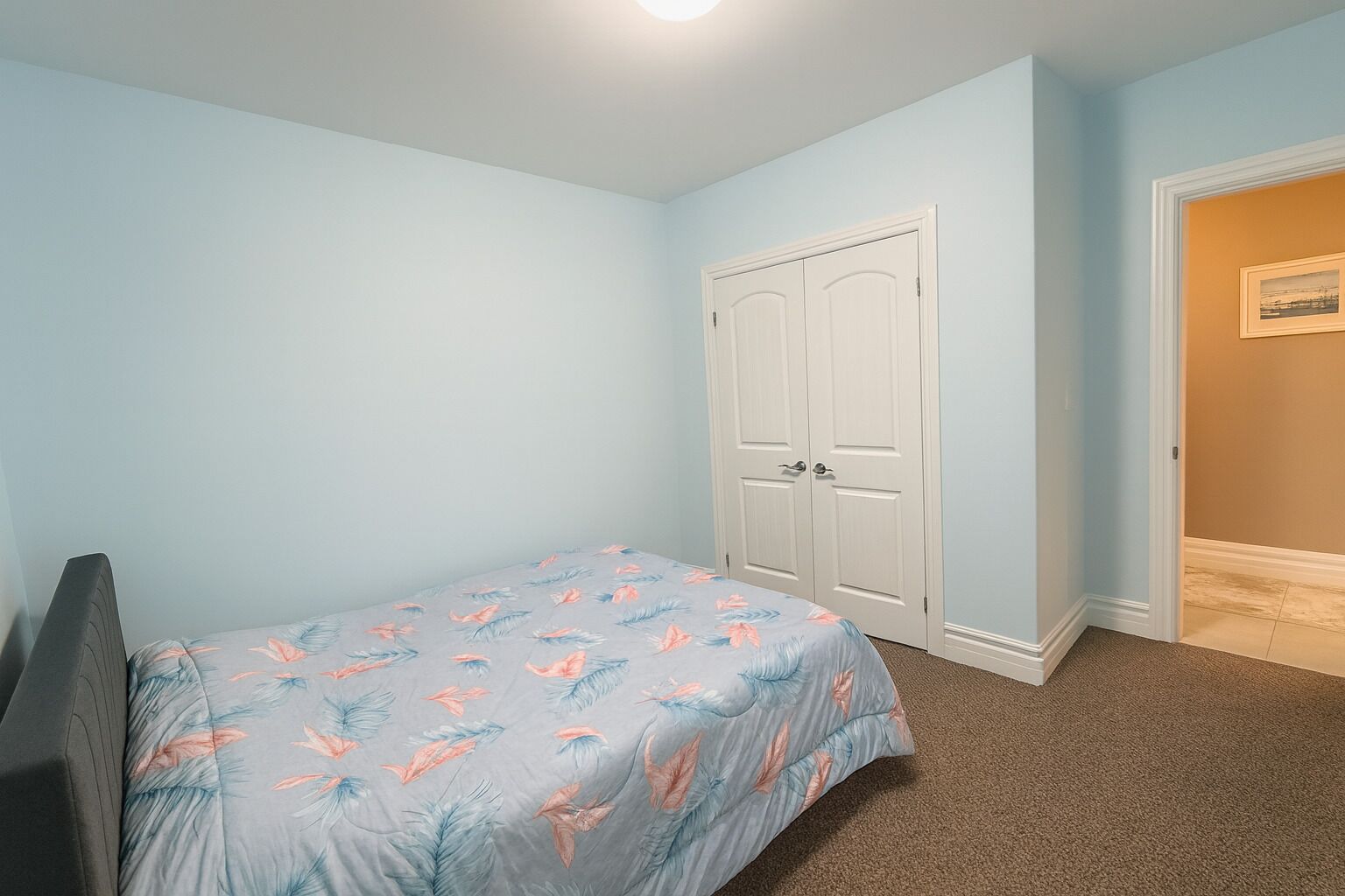 Une chambre à coucher comprenant un lit, une armoire et une porte donnant sur une autre pièce.