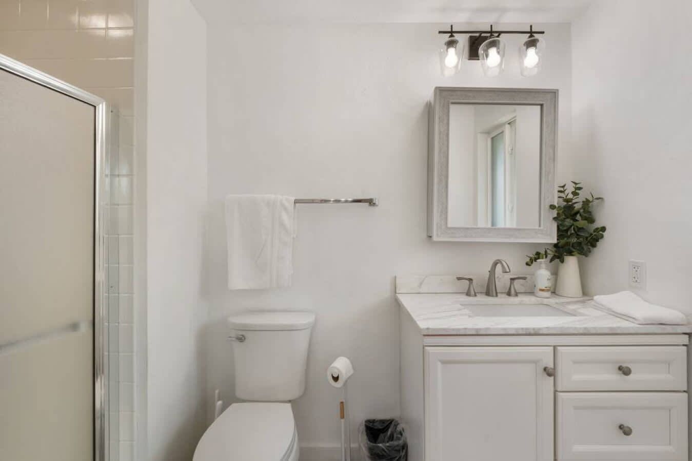 A bathroom with a toilet, sink, and shower.