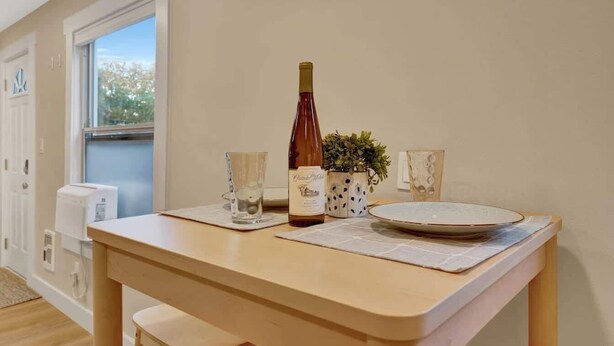 A dining table with a bottle of wine, two glasses, and a plate. - Westlake Nest | Minutes to DT | Quiet & Renovated! (Seattle)