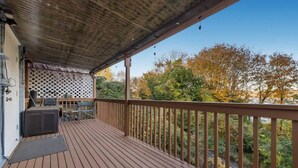 A wooden deck with a covered area, a grill, and a seating area with a table and chairs. - Westlake Nest | Minutes to DT | Quiet & Renovated! (Seattle)