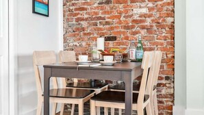 Une table à manger avec des chaises, un mur en briques et un tableau encadré accroché au mur.