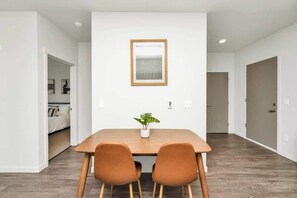 A modern dining area with a wooden table, two brown chairs, and a potted plant. - Skyline Haven | Downtown Seattle | 30+ Nights! (Seattle)